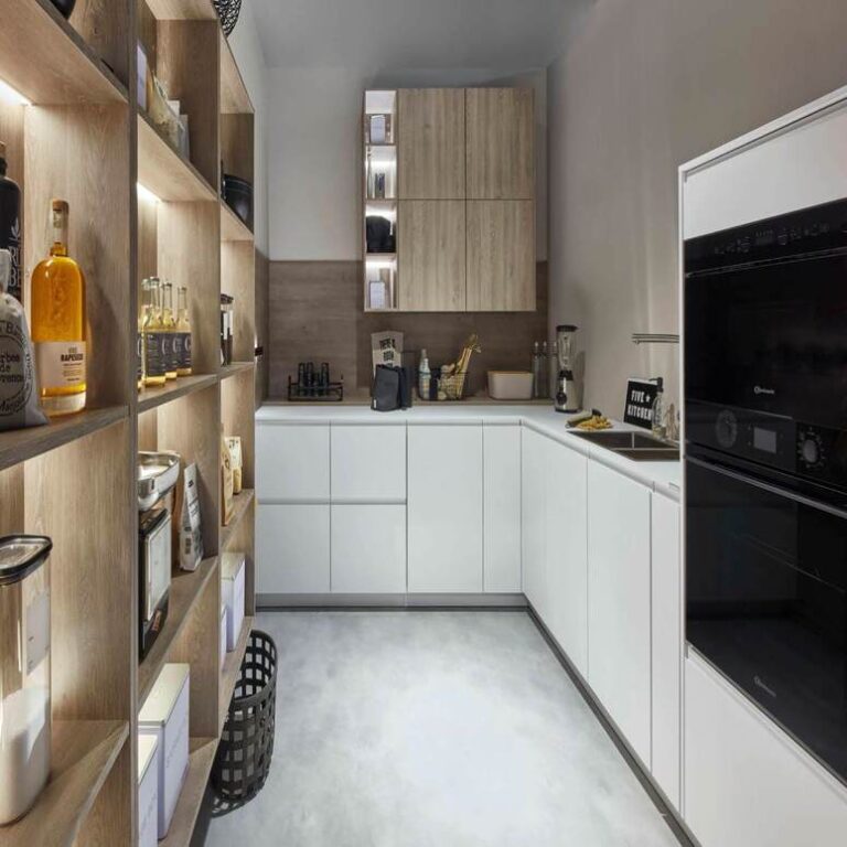 Moderne weiße Küche mit Hochschränken, Holzregal und schwarzen Einbaugeräten – Küchenangebote Trier